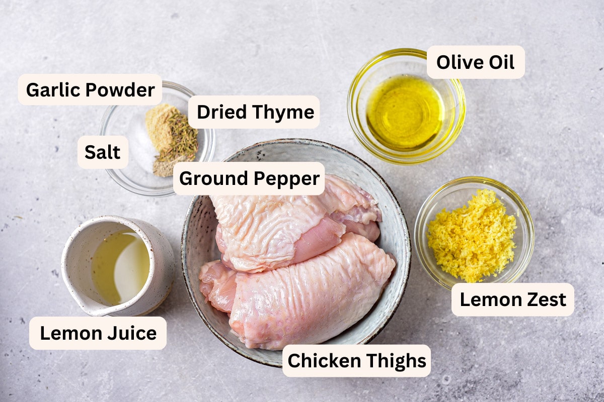 ingredients to make lemon chicken thighs in bowls with labels on counter.