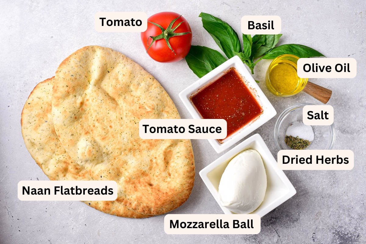 ingredients to make air fryer naan pizza on counter in bowls with labels.