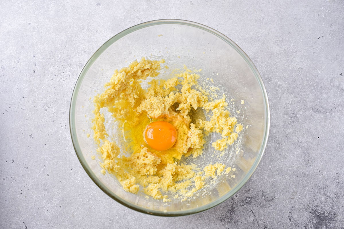 raw egg and whipped butter in clear mixing bowl on counter.