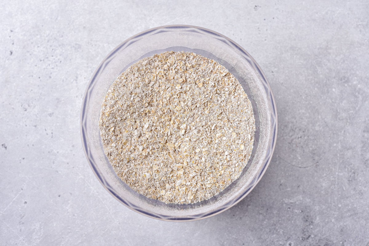 large glass mixing bowl filled with raw oats sitting on counter top.
