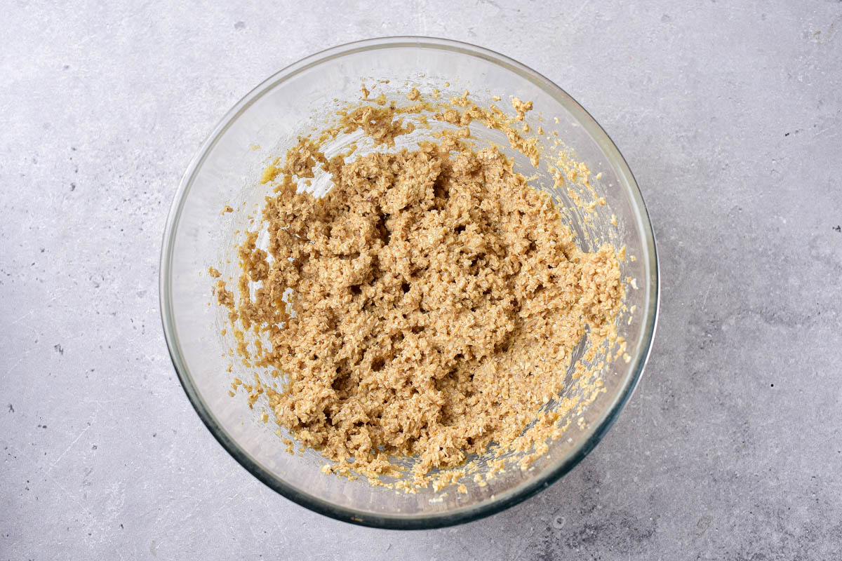 raw oatmeal cookie batter in clear mixing bowl on counter.