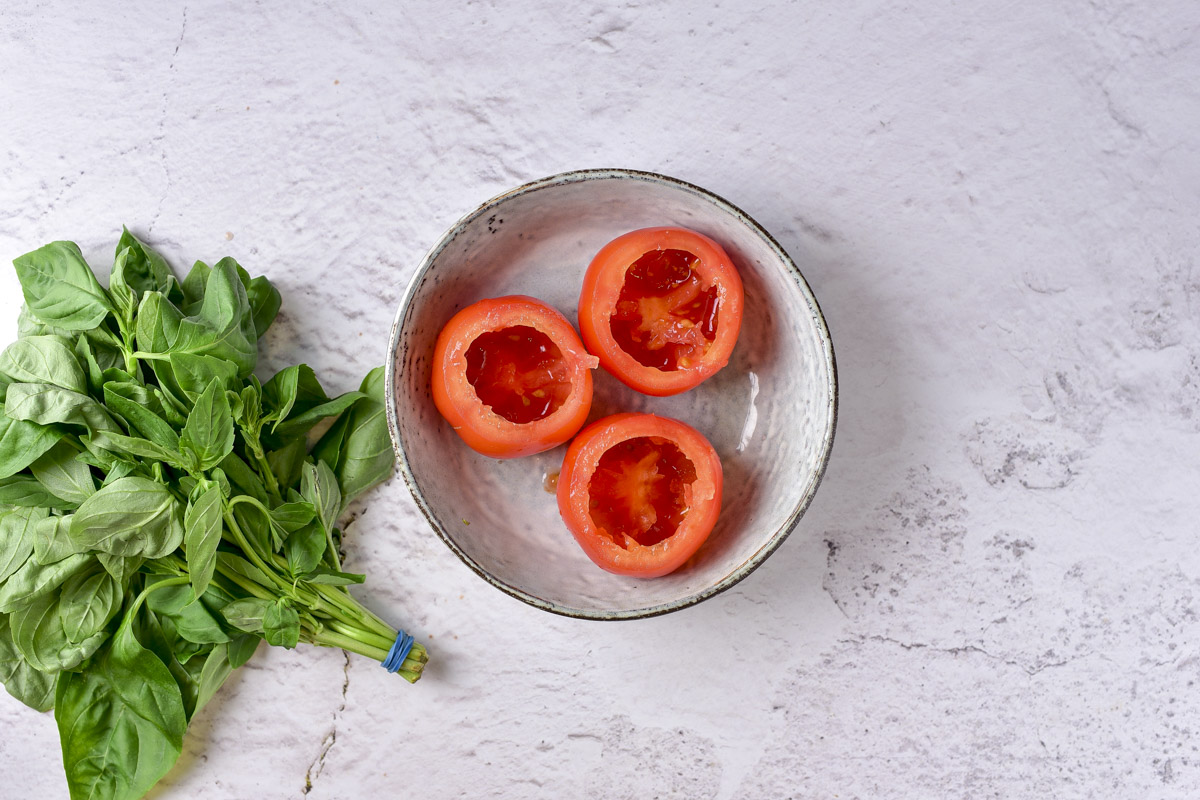 three red tomatoes on a plate with the cores removed.