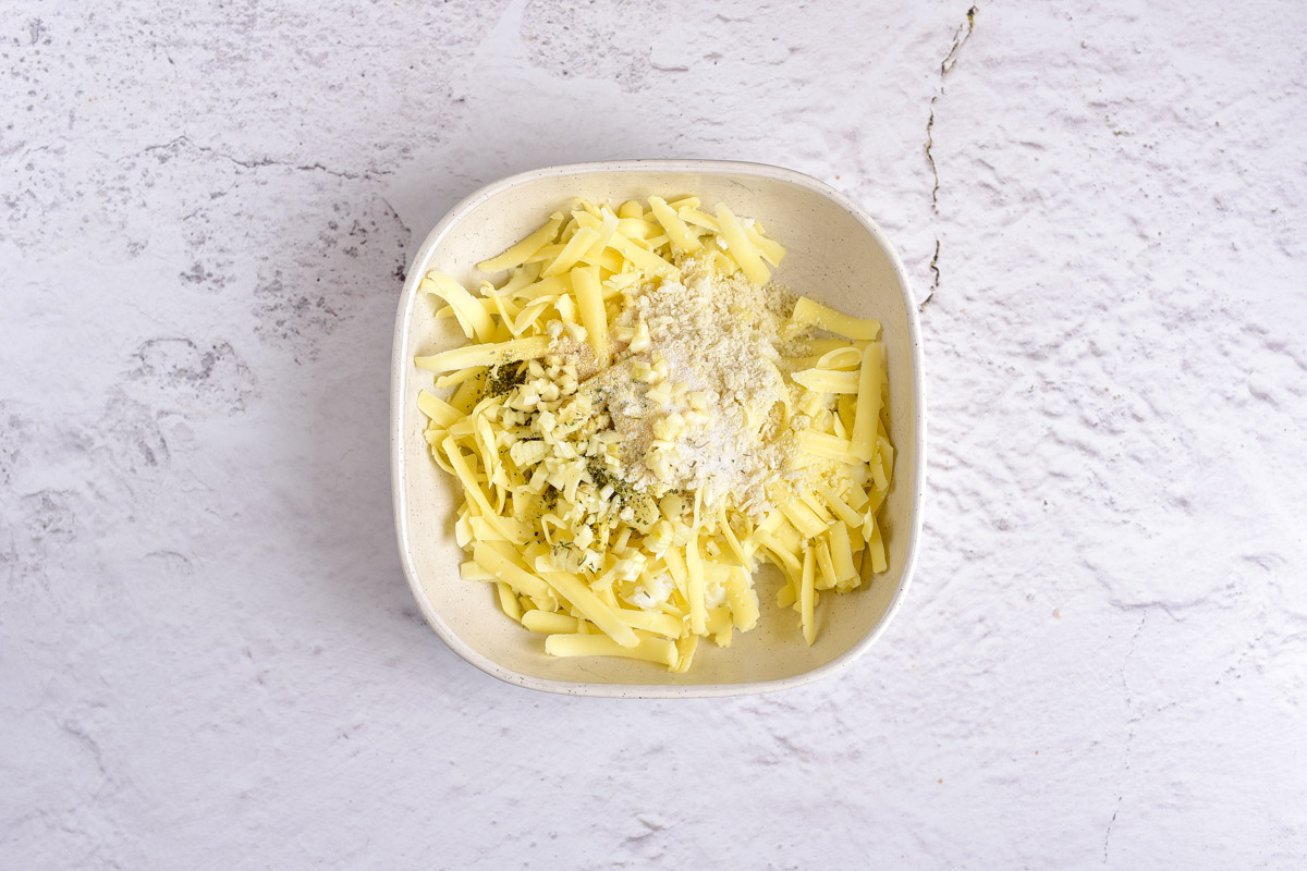 cheese, breadcrumbs, and spices mixed together on a white plate on counter.