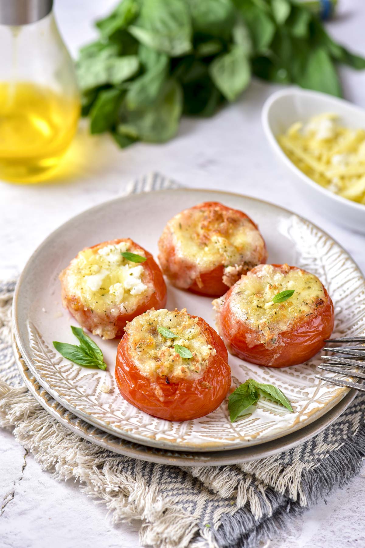 four stuffed tomatoes on a plate sitting on a cloth on a counter.