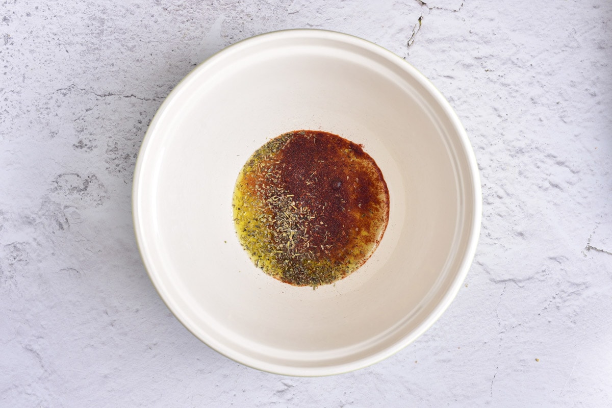 oil and seasonings in white bowl on counter.