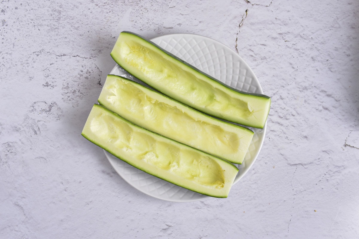 three half zucchinis with the middles scooped out on plate.