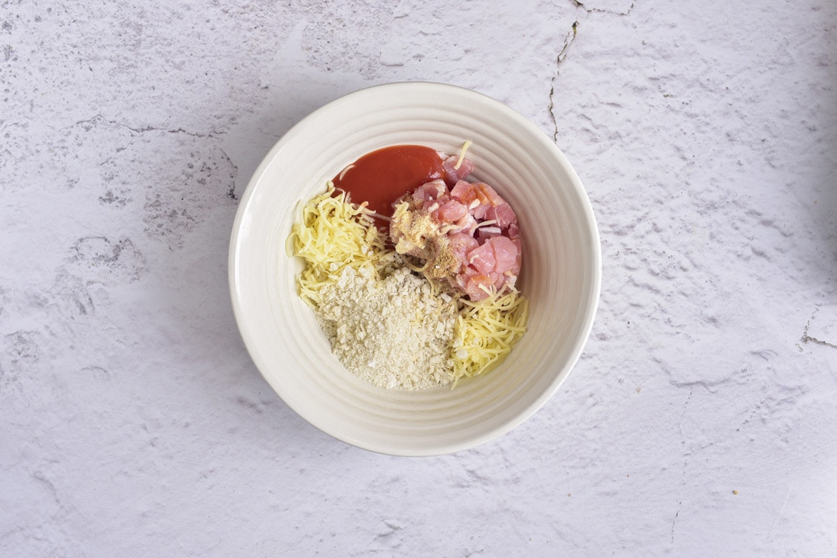 white bowl filled with chopped bacon cheese and spices sitting on counter top.