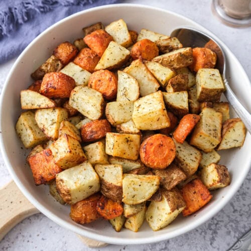 bowl of air fried carrots and potatoes on counter with spoon in bowl.