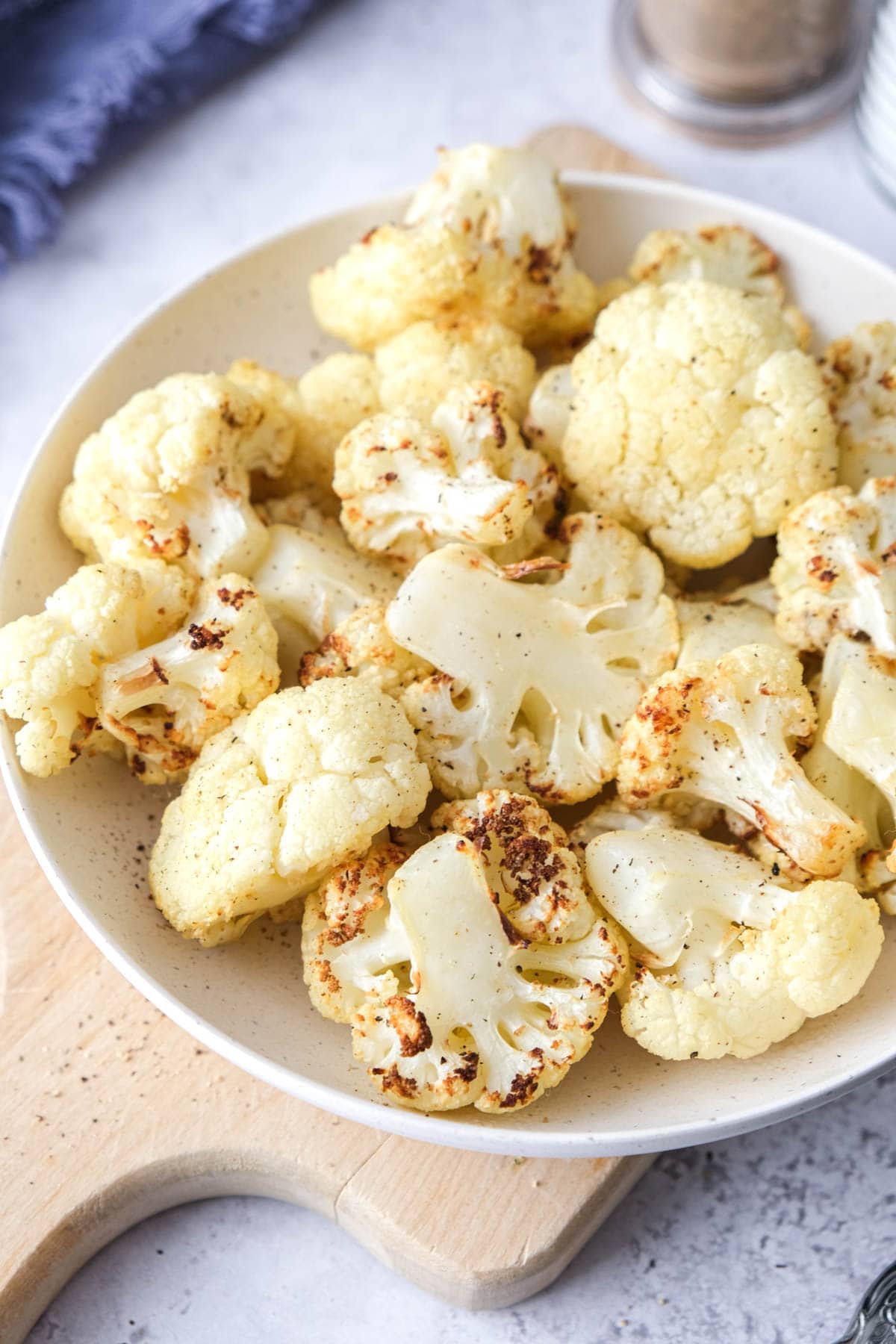 bowl of air fried cauliflower on wooden board on counter.