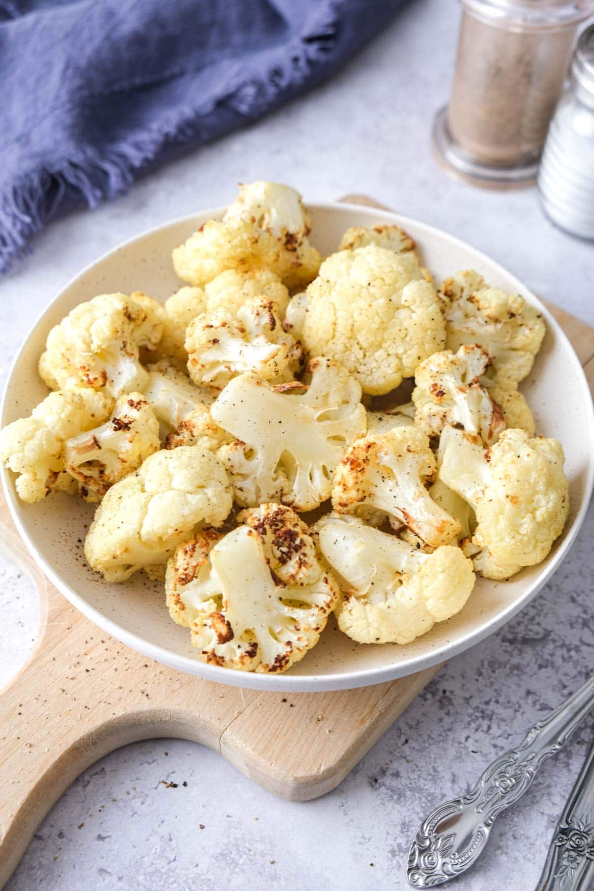 bowl of crispy cauliflower on wooden board on counter.