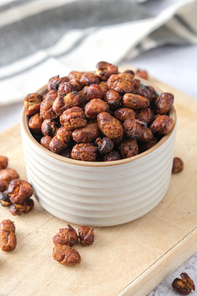 little bowl of crispy fava beans sitting on wooden board.