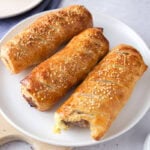 crispy brown sausage rolls on white plate on counter.