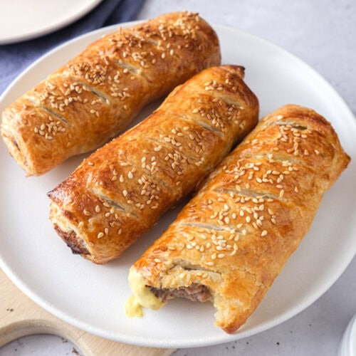 crispy brown sausage rolls on white plate on counter.