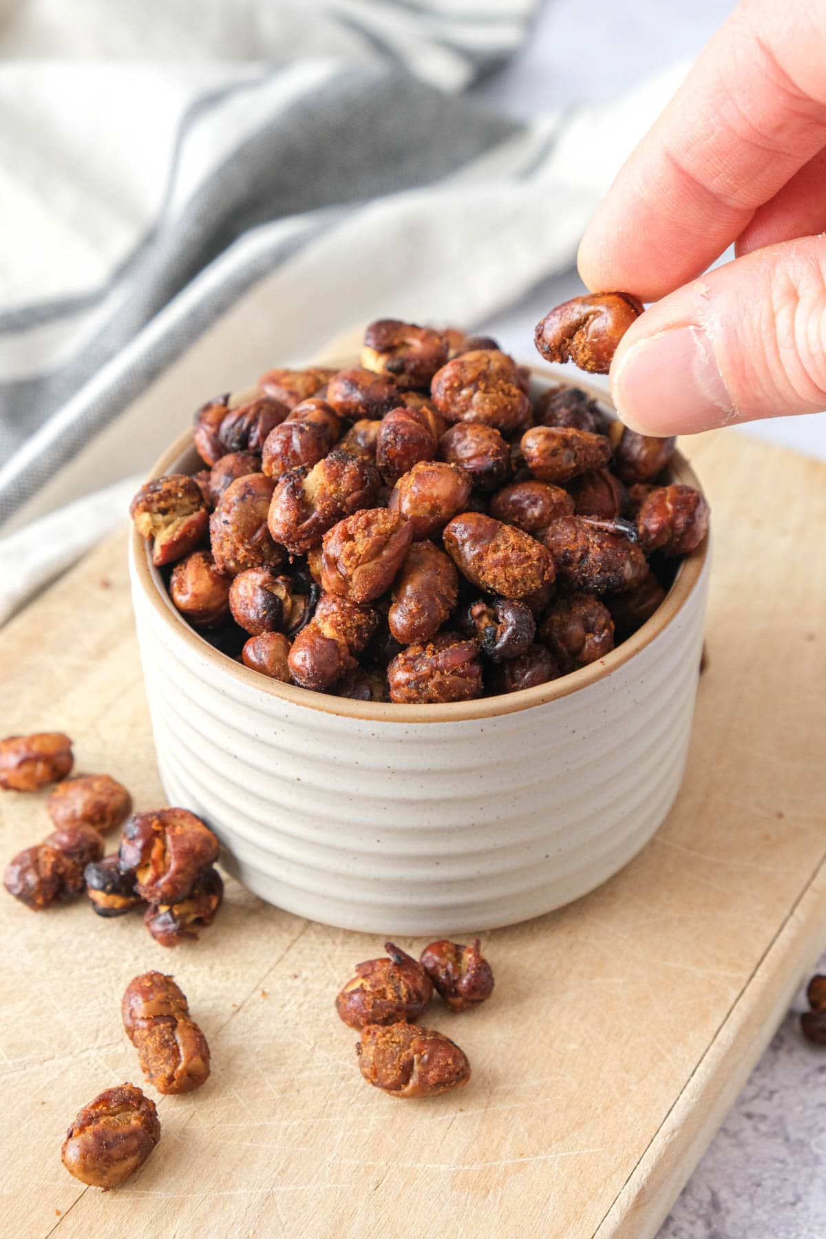hand removing fava bean from bowl of other fava beans.