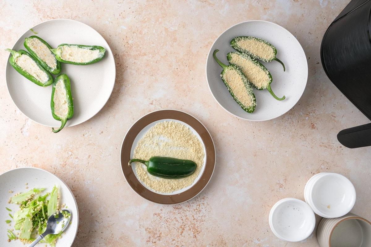 half a jalapeno pepper dipped in panko breadcrumbs with more pepper halves beside.