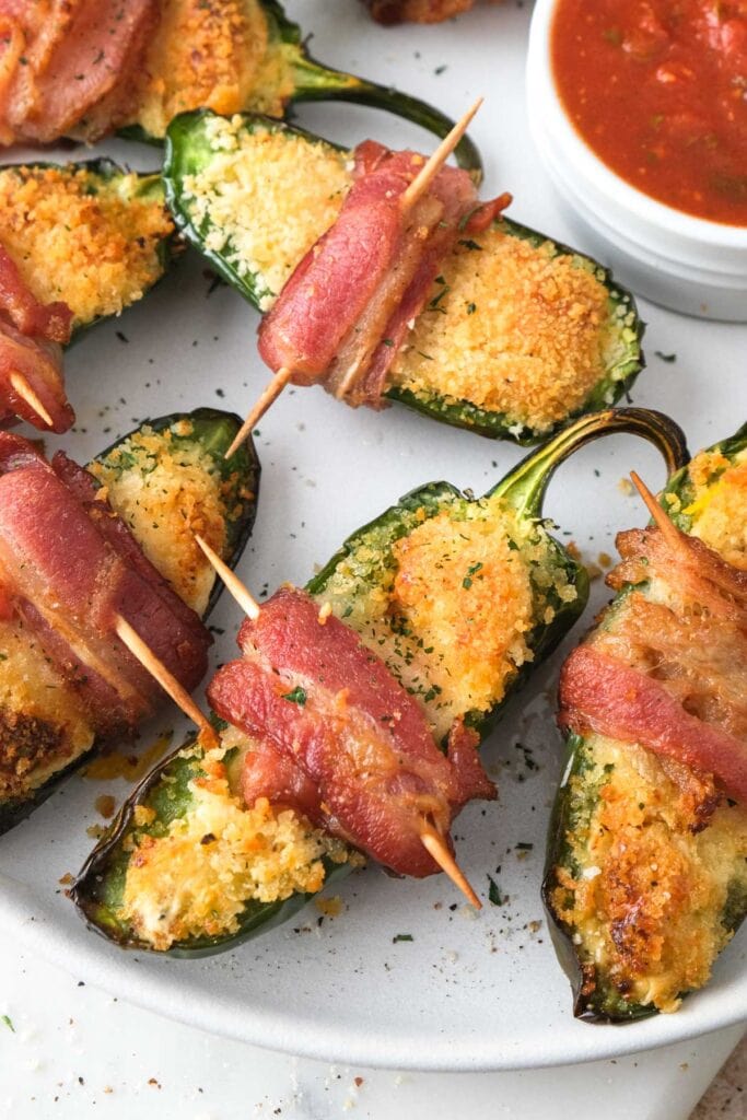 crispy jalapeno poppers wrapped in bacon sitting on plate.