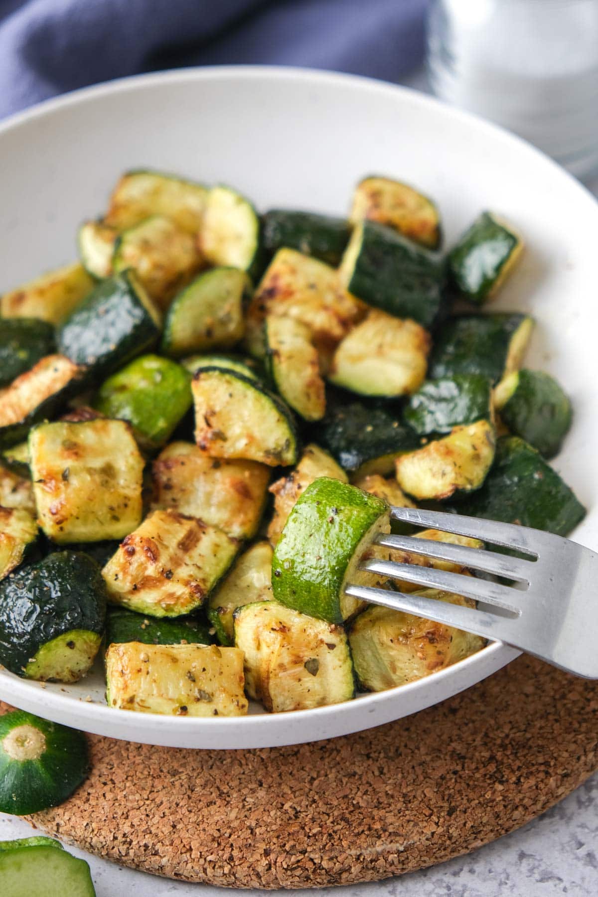 piece of zucchini on end of fork above other pieces in bowl.