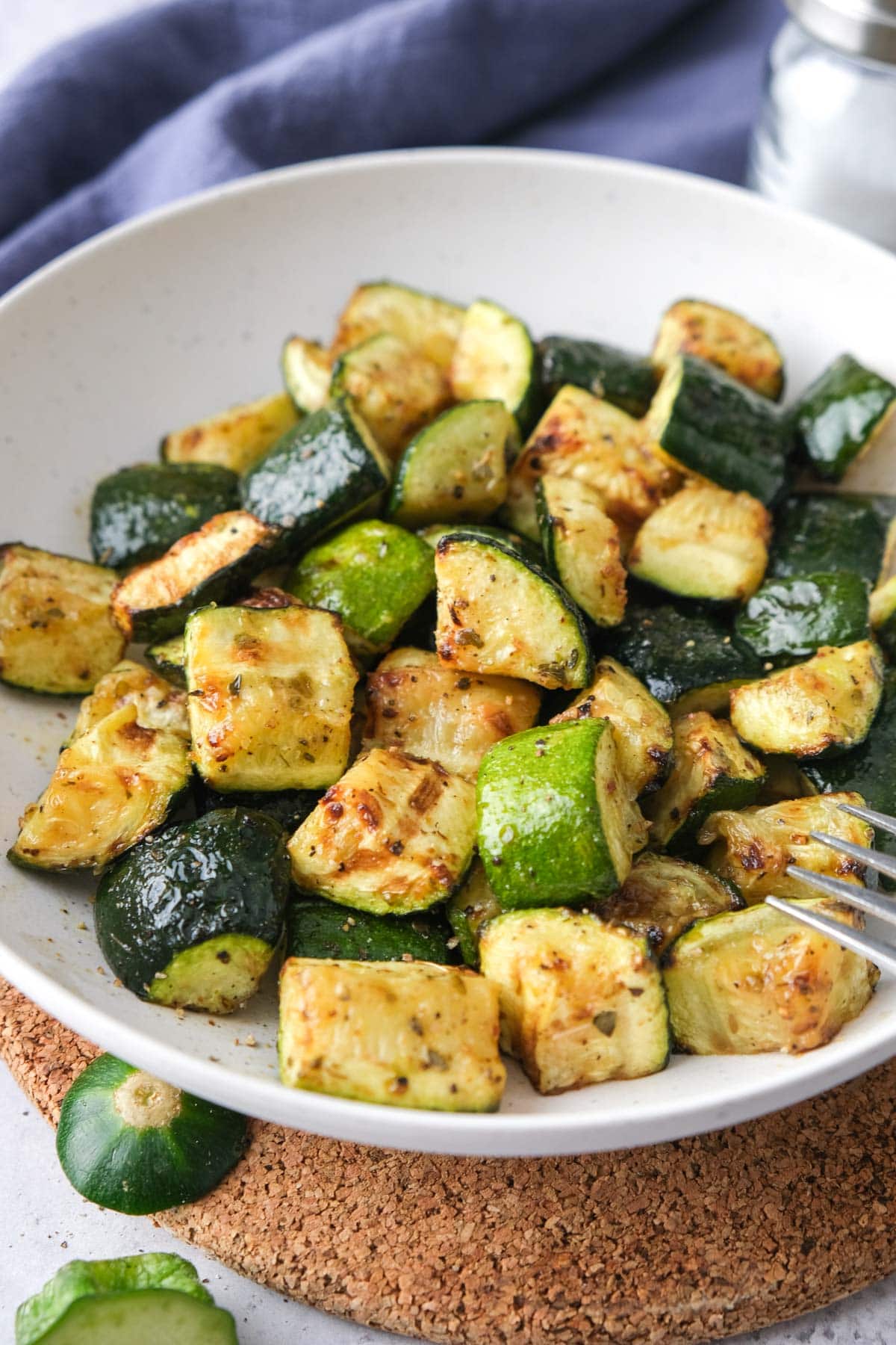 bowl of air fryer zucchini pieces sitting on cork board.