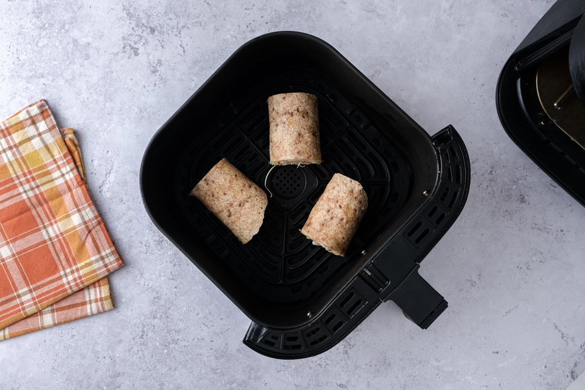 cut pieces of turkey roll-ups sitting in air fryer basket.