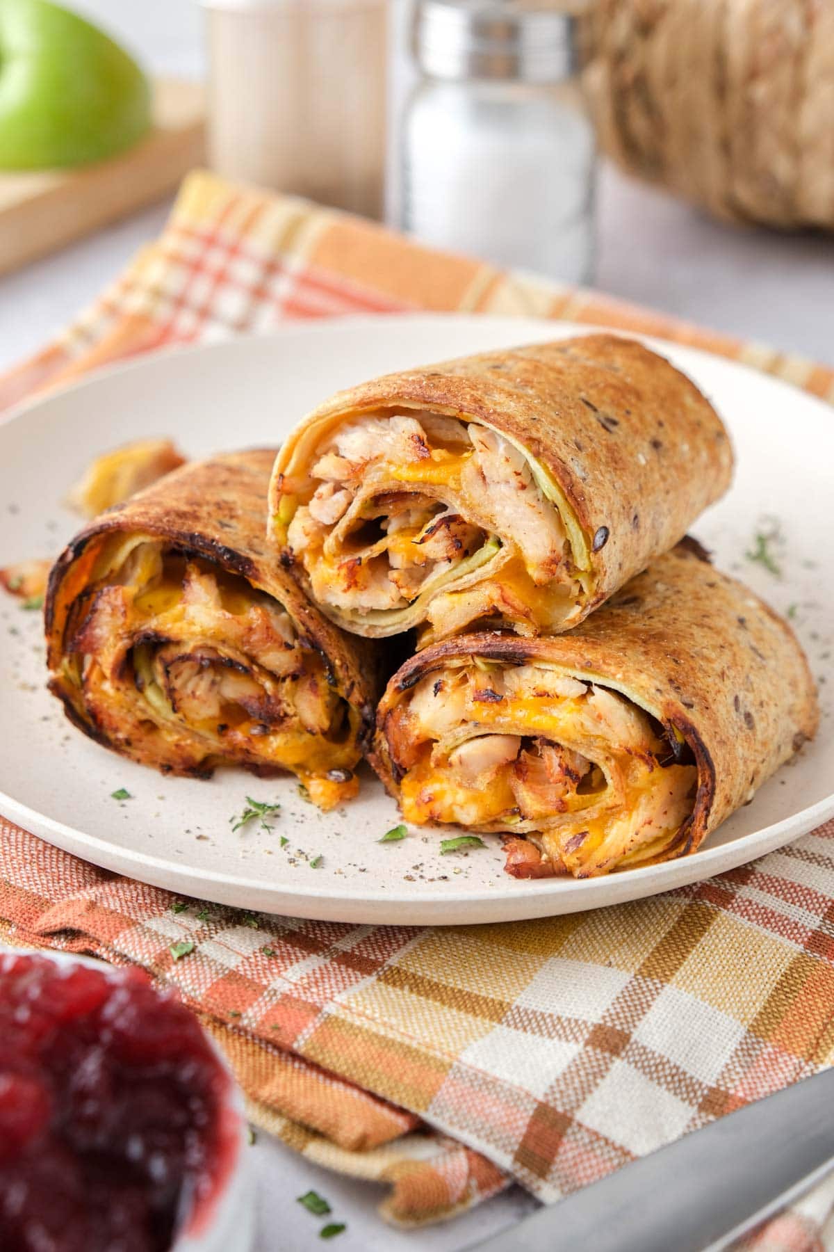A plate of turkey and cheese burritos on a table cloth.