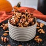 small bowl of roasted pumpkin seeds on black plate.