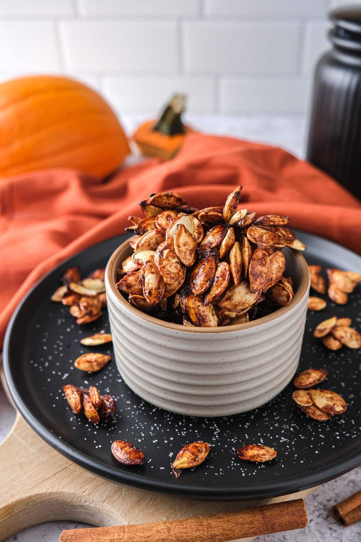 bowl of pumpkin seeds covered in sugar on black plate.