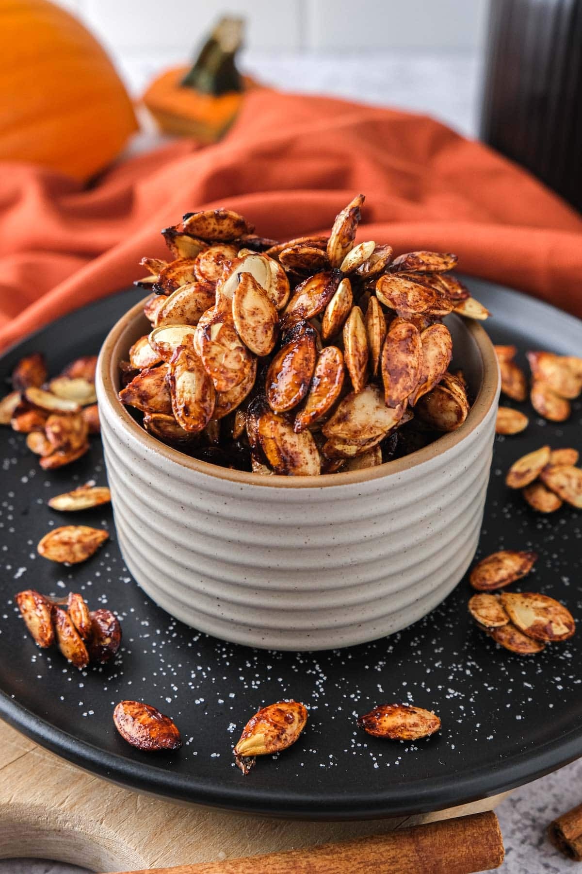 small bowl of crispy pumpkin seeds on black plate.