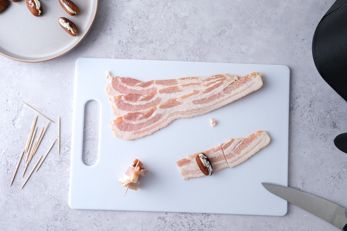 dates being wrapped in bacon spices on cutting board.