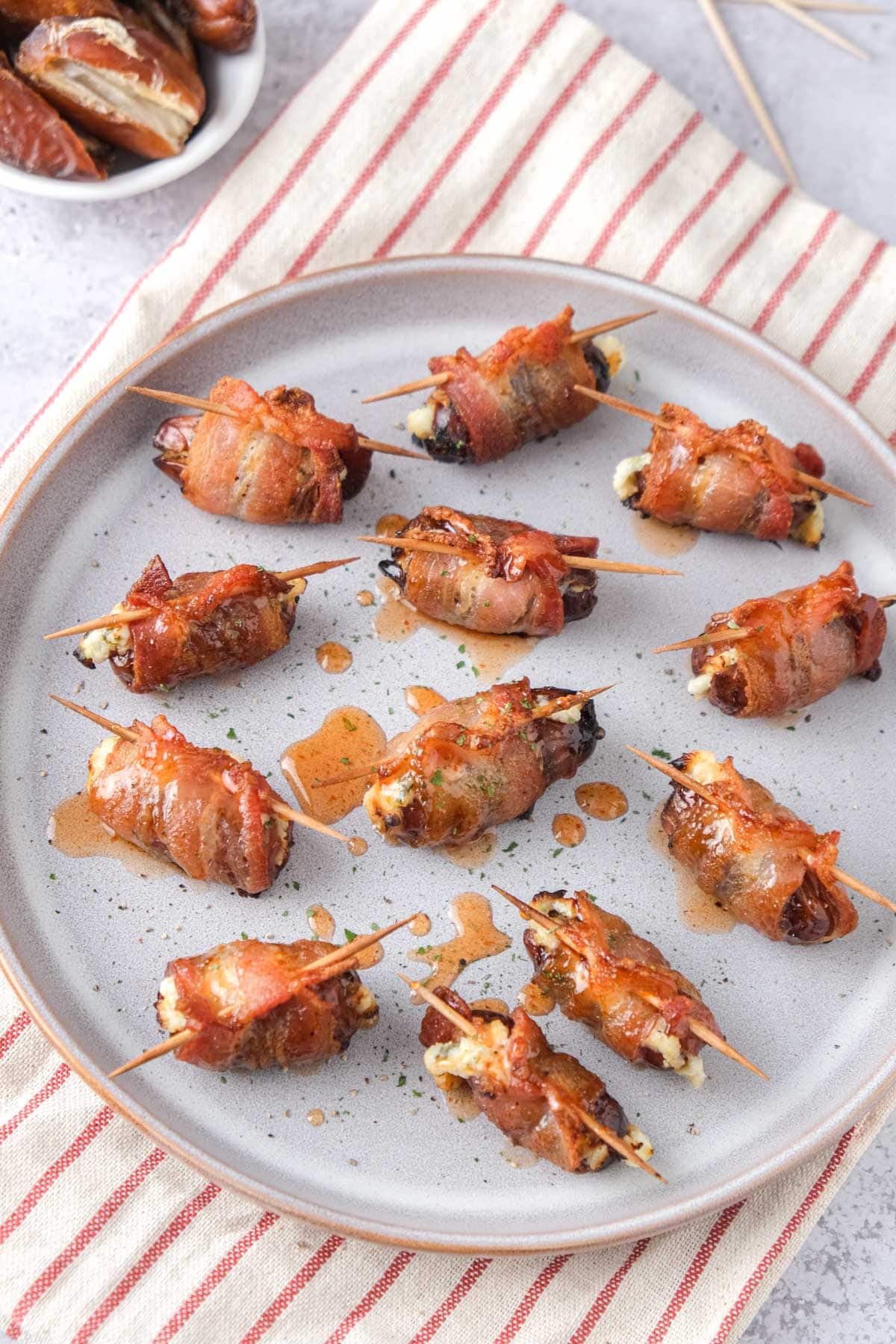 bacon wrapped dates drizzled in hot honey seen from above on a plate.