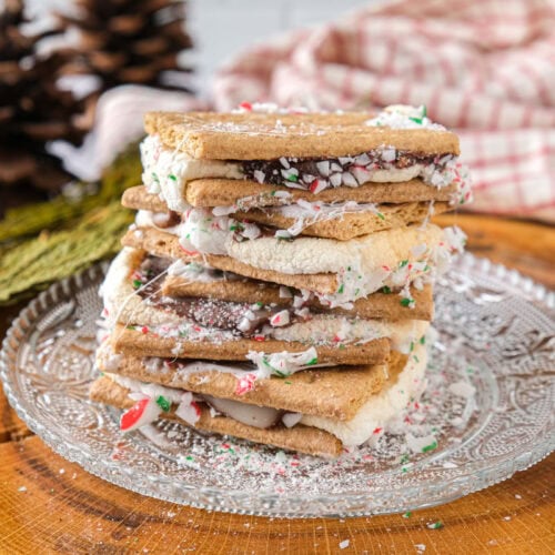 stack of messy smores on glass plate on wooden board.