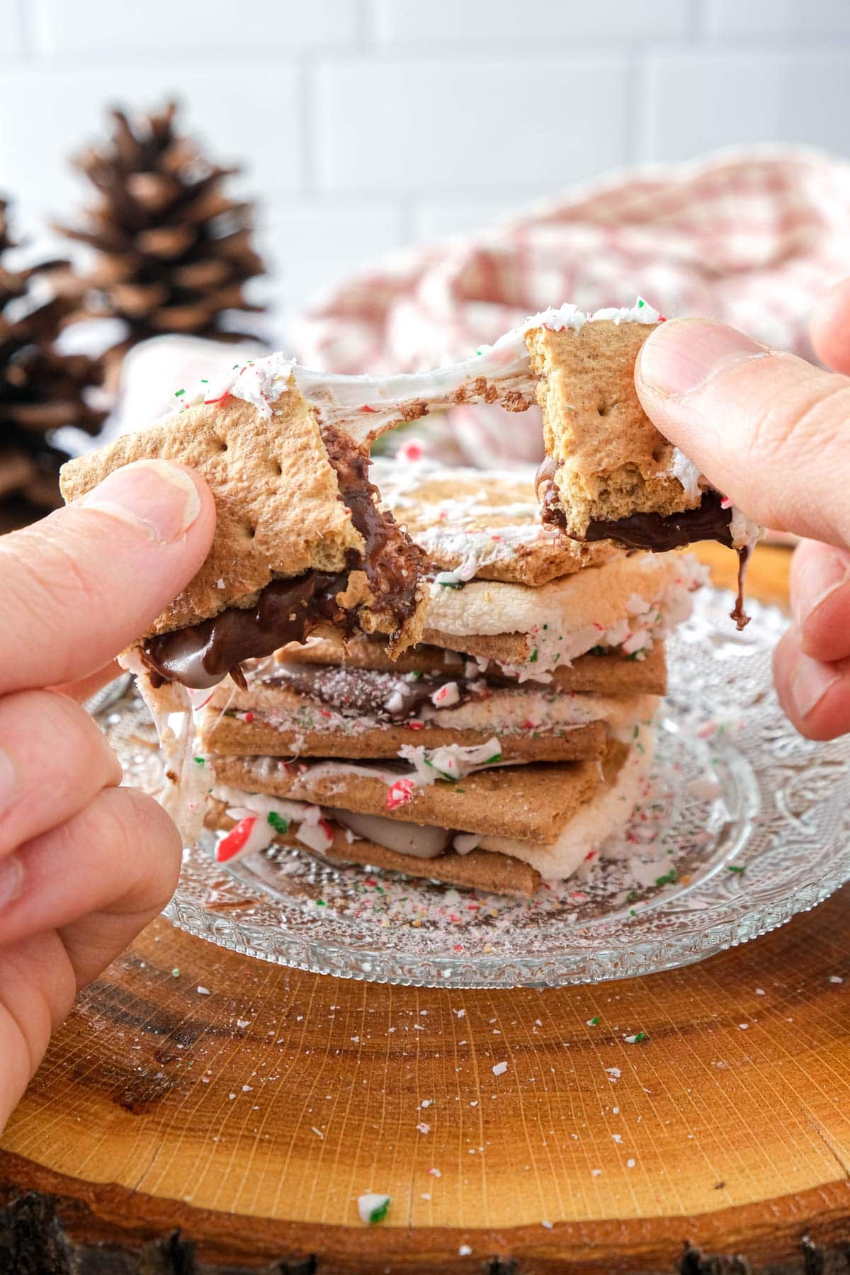 hands breaking peppermint smore in half with more smores behind.