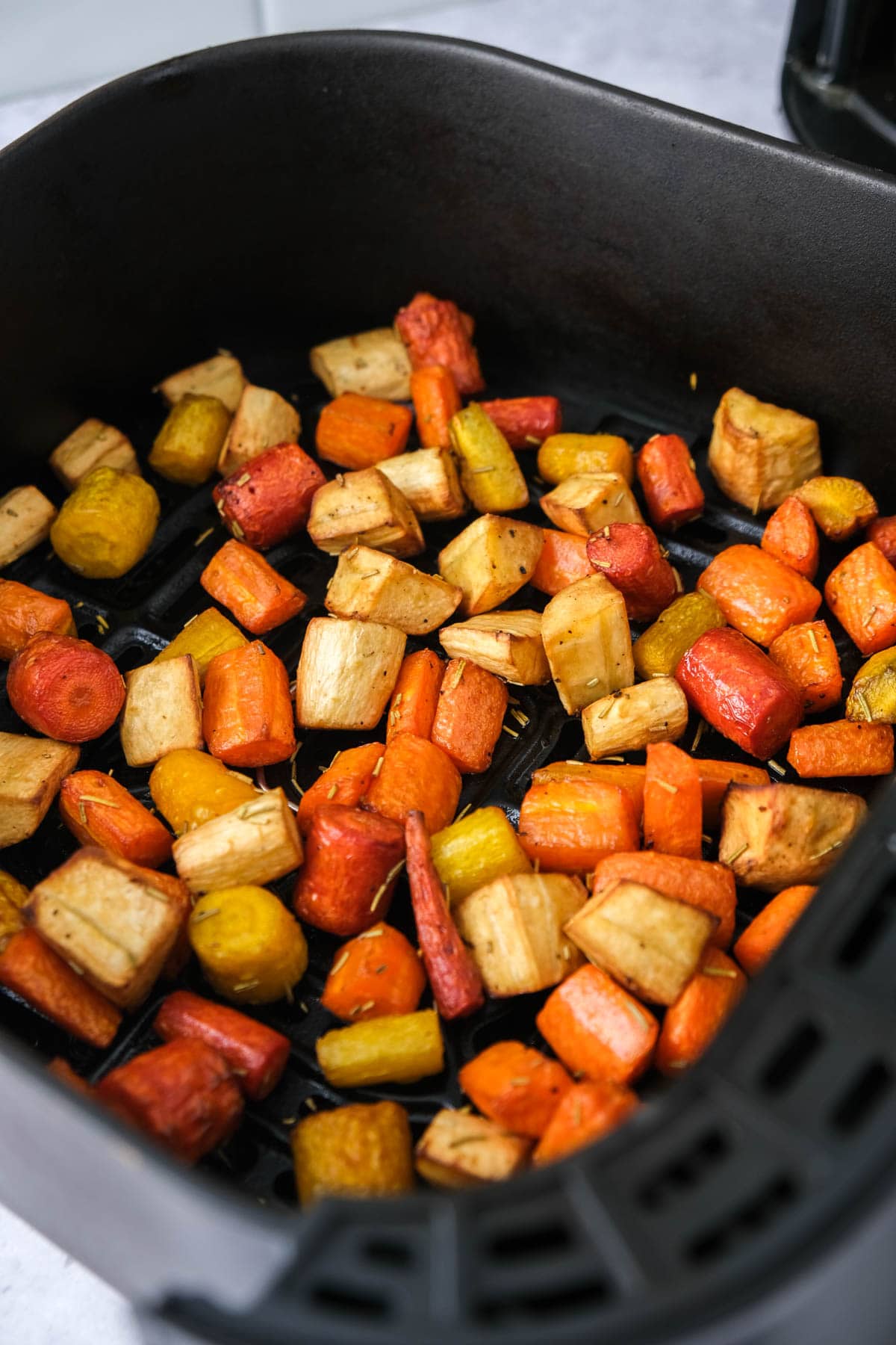 cooked root vegetables in air fryer basket.