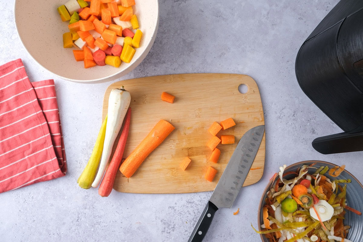knife cutting carrot into pieces on wooden board.