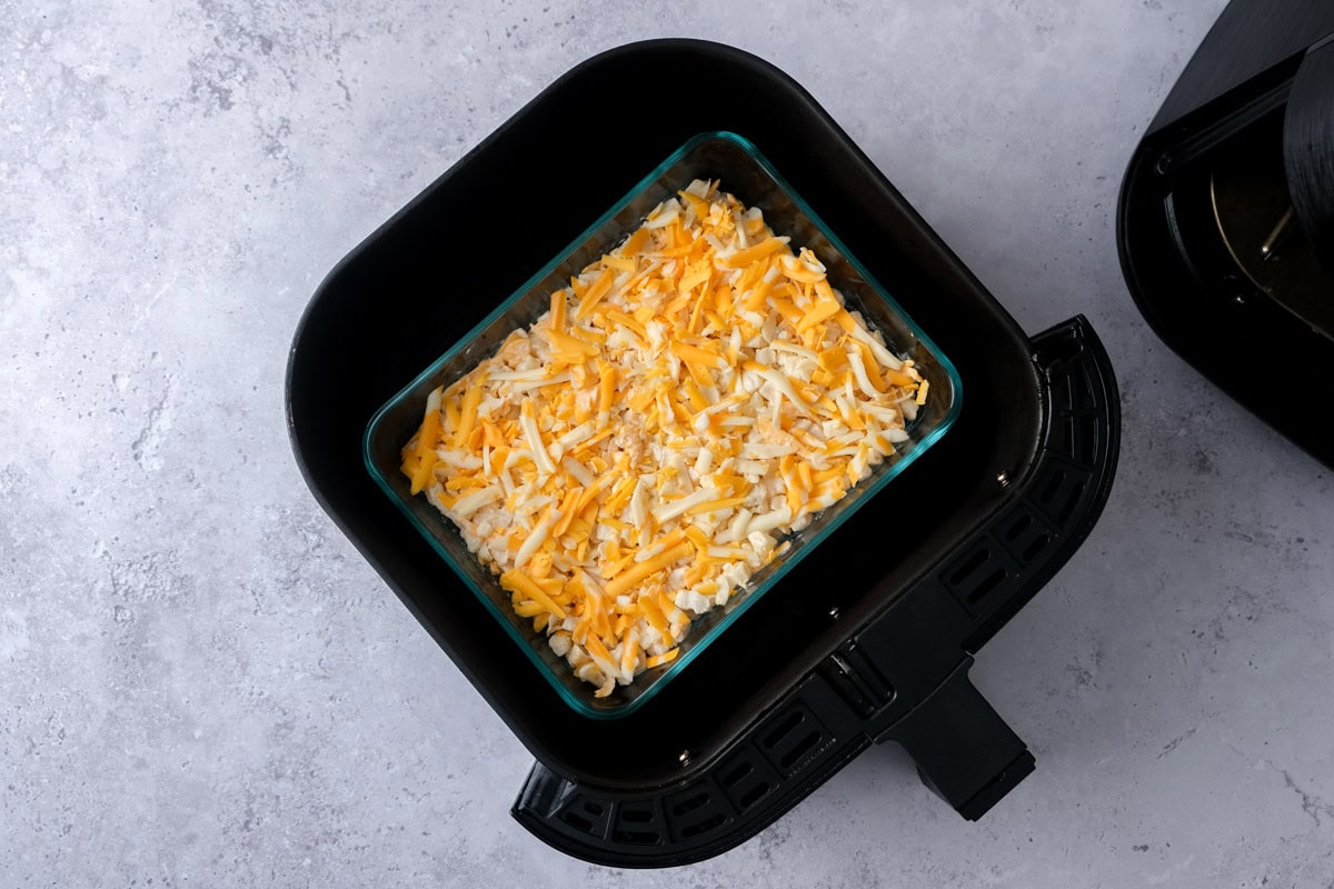 cheese potato bake in glass dish sitting in air fryer basket.