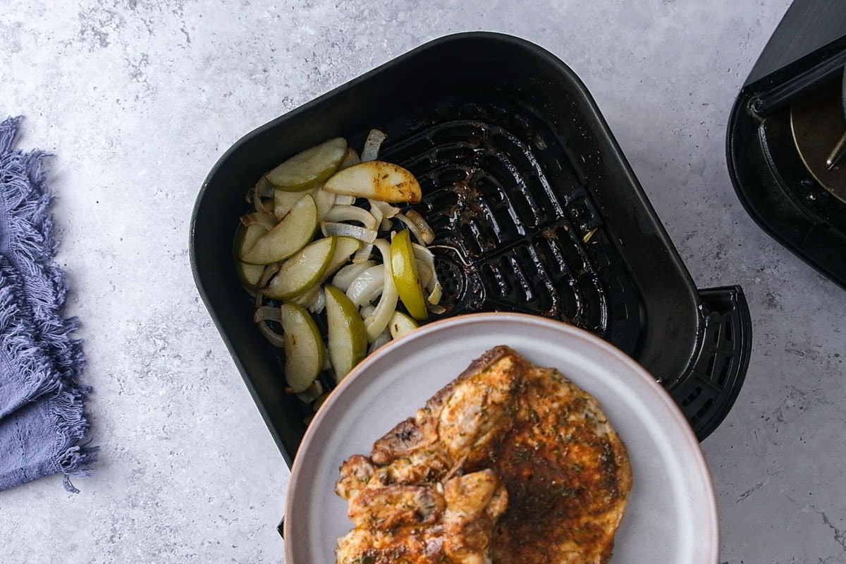 pork chops on plate being removed from apples in air fryer.