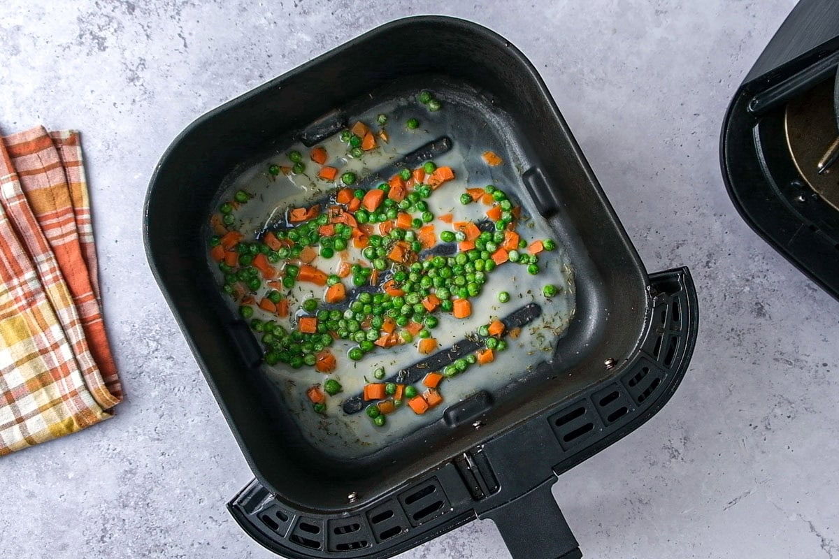 thickened broth and vegetables in air fryer basket on counter.