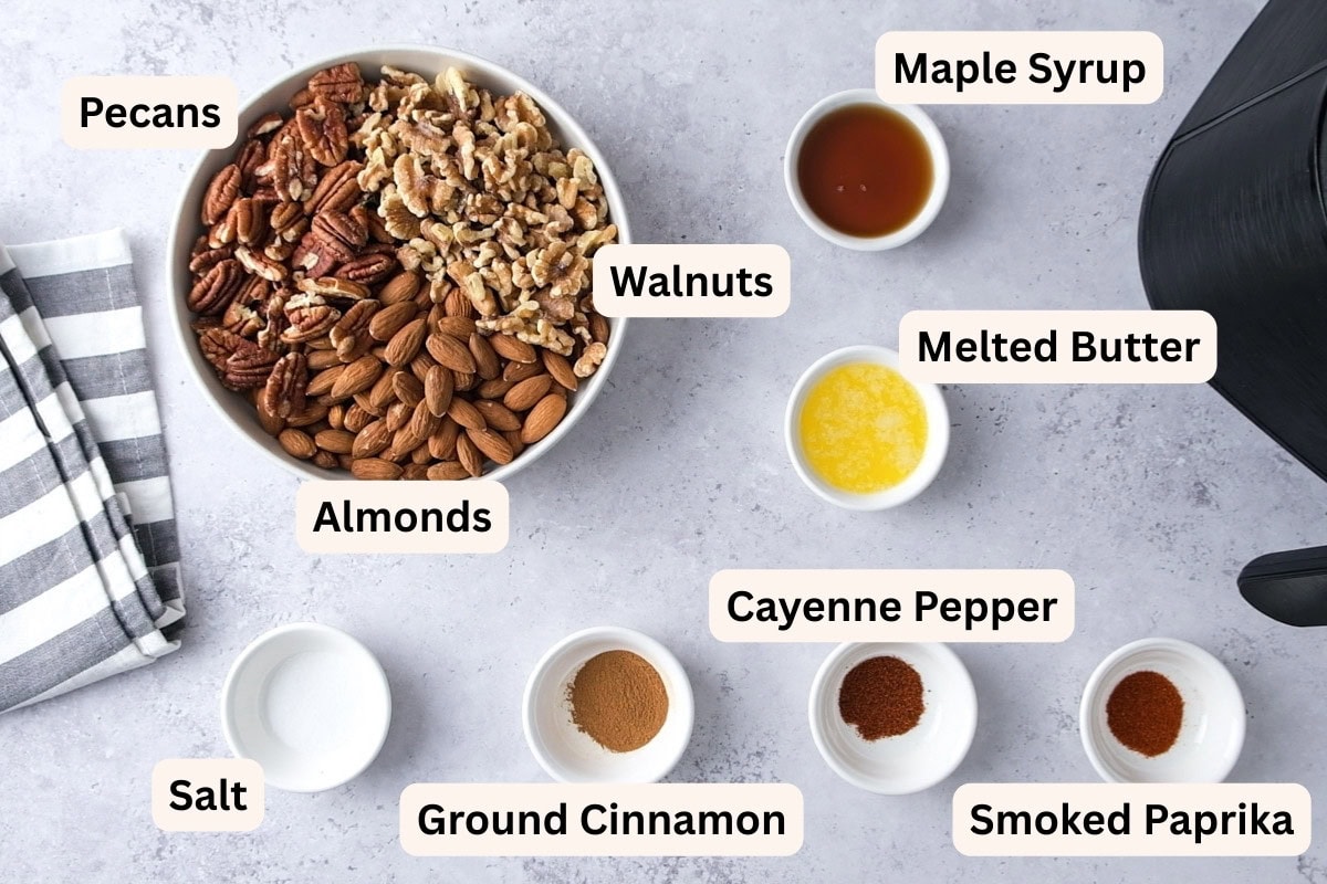 ingredients to make mixed nuts on a counter in bowls with labels.