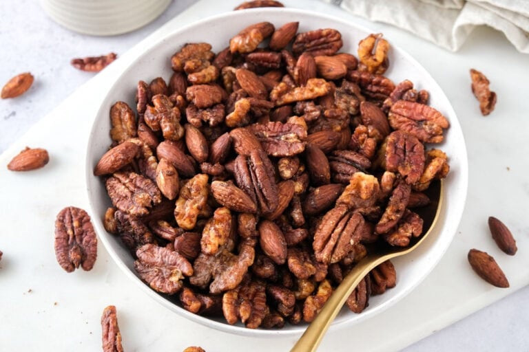 sweet and spicy nuts in white bowl with golden spoon sticking out.