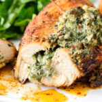 cheese and spinach stuffed chicken breast on plate with piece cut off the front.