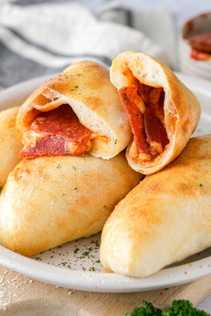 mini calzone cut in half on top of other calzones on plate.