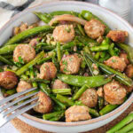 bowl of sausage and green vegetables on counter with silver fork in the bowl.