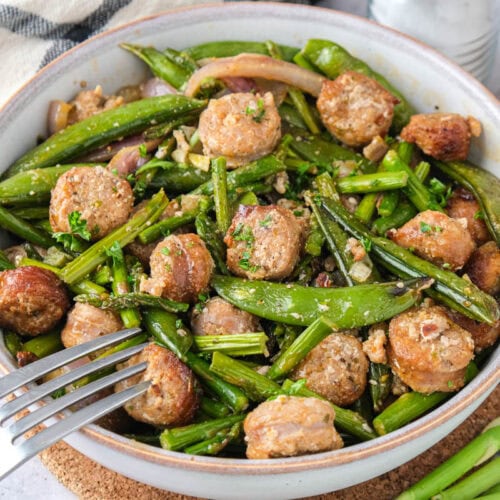 bowl of sausage and green vegetables on counter with silver fork in the bowl.