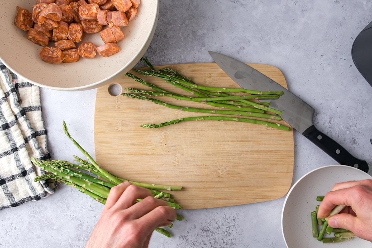 hand snapping ends off green asparagus on counter top.