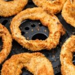 golden brown onion rings in air fryer basket with text overlay "air fryer onion rings".