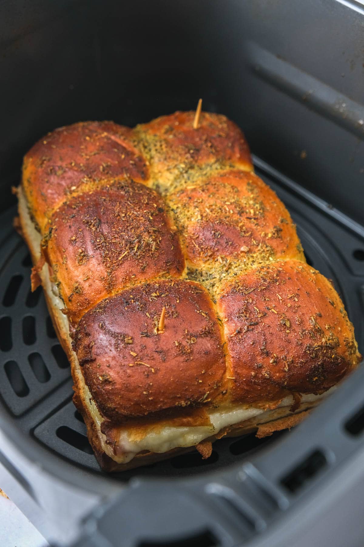 crispy brown ham and cheese sliders in air fryer basket.