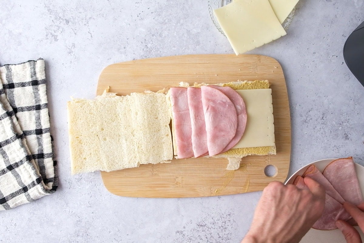 folded deli ham on cheese on slider buns sitting on counter.