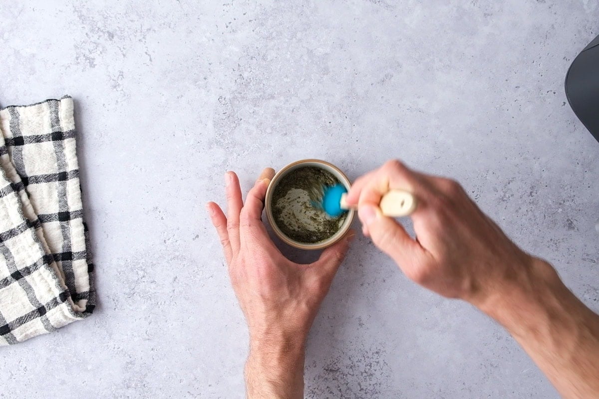 hand mixing butter and spices in small ramekin on counter.