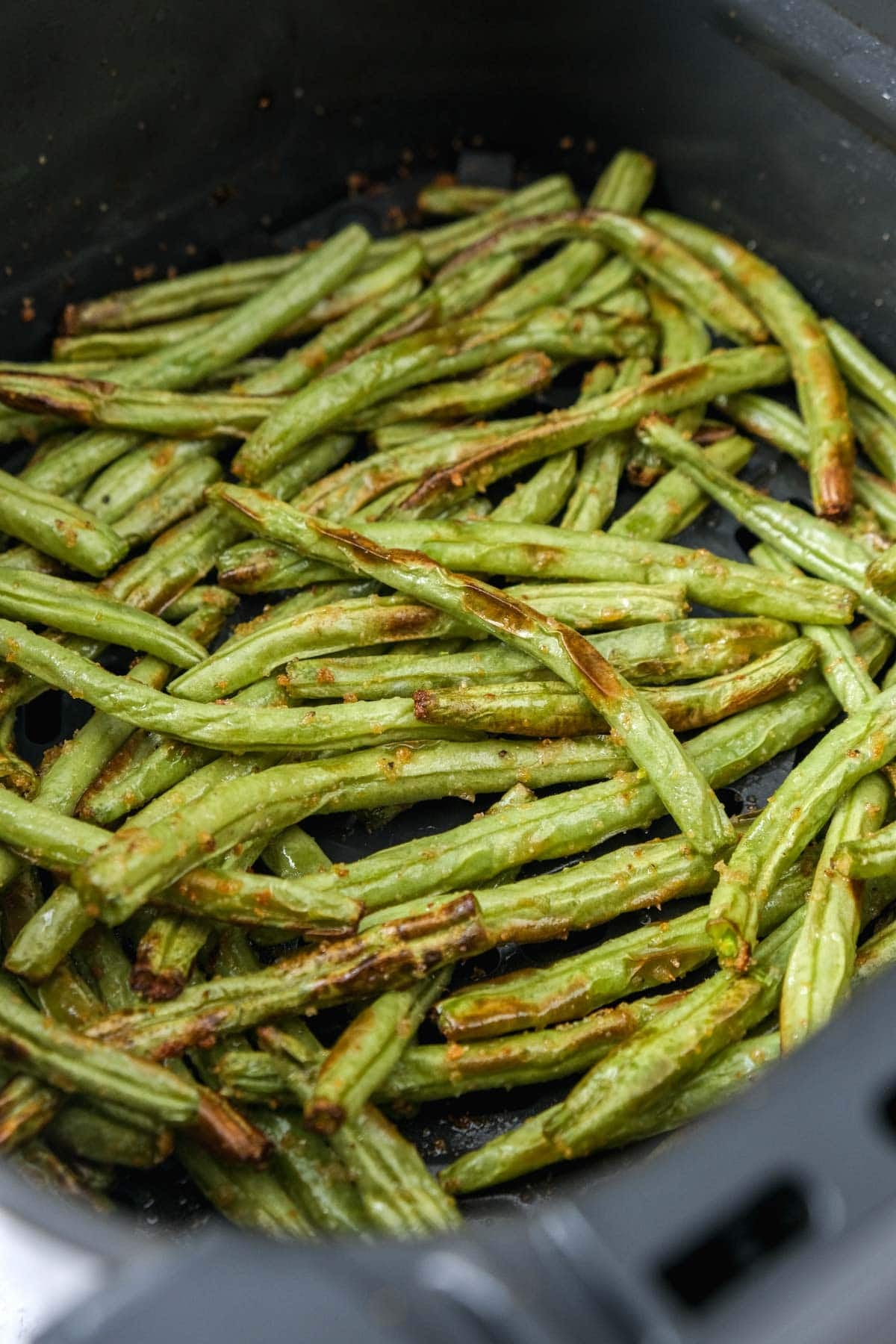 cooked green beans in air fryer basket.