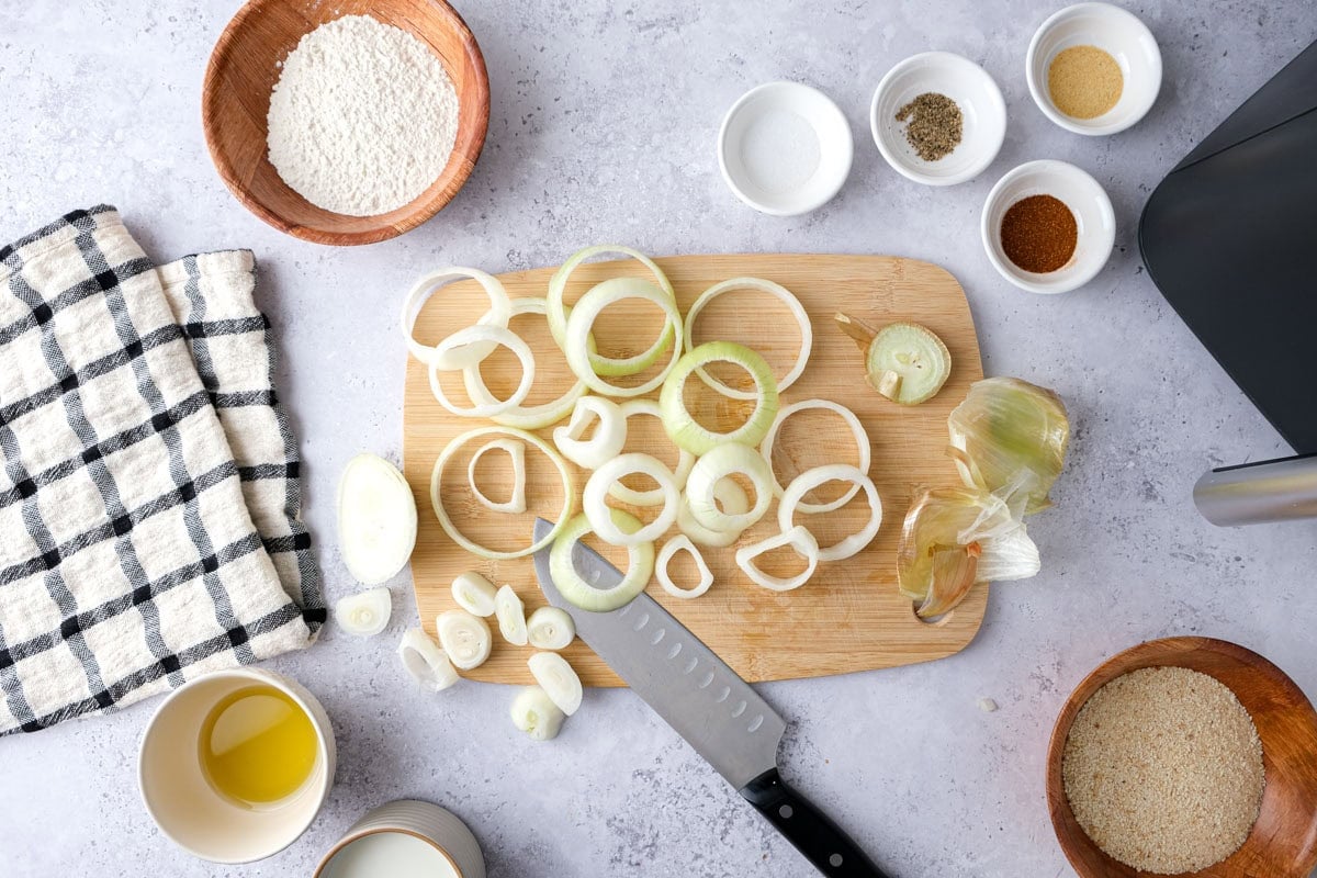 raw onion rings on cutting board being separated from the other onion pieces.