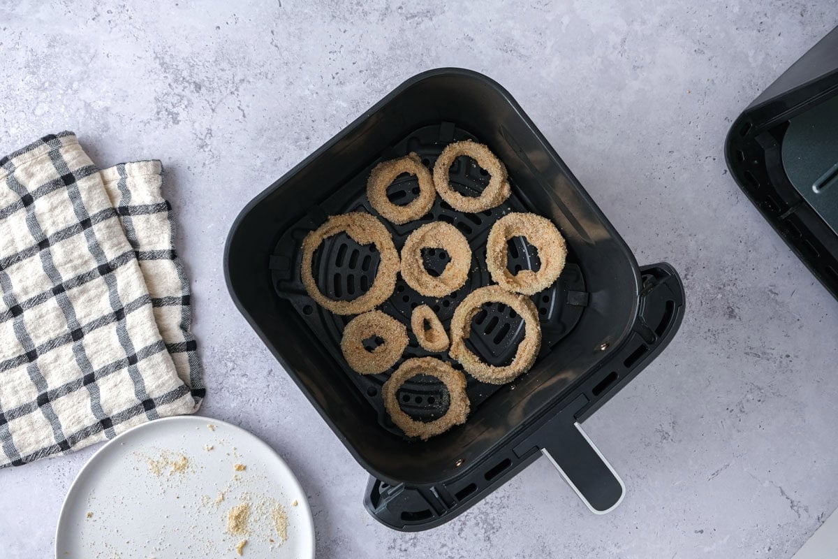 onion rings raw in air fryer basket.